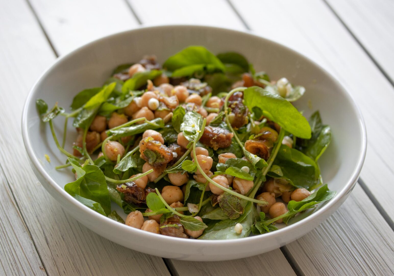 cresson, garbanzo beans, dates salad served cresson, garbanzo beans, dates salad in a white plate